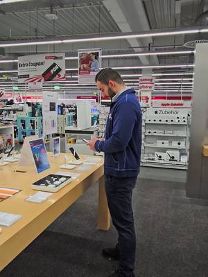 Verkäufer im Elektromarkt mit iPhone-Angeboten im O2-Tarif